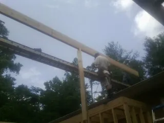 Carpenter setting a ridge beam over a new addition frame — Ice Dam Removal by Roofing Brothers in Tennessee Colony