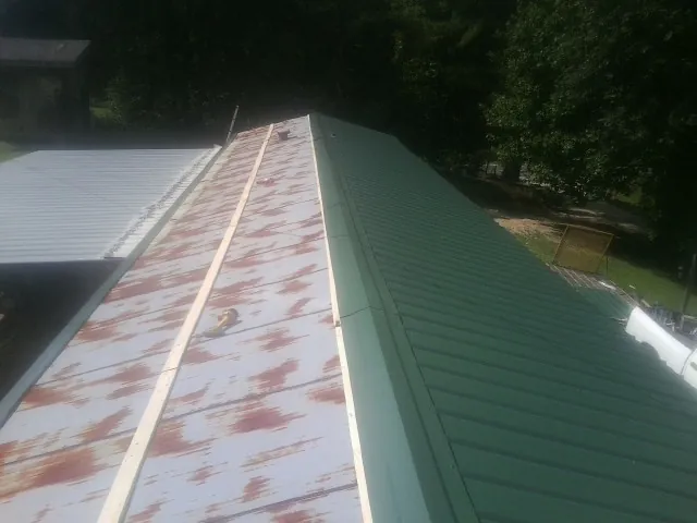 Old rusted panels beside newly installed green metal roofing — Wind Damage Roof Repair by Roofing Brothers in Tennessee Colony