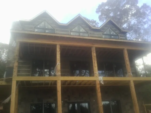 Dormers and porch framing on a large log home under construction — Roof Coating work by our crew in Tennessee Colony