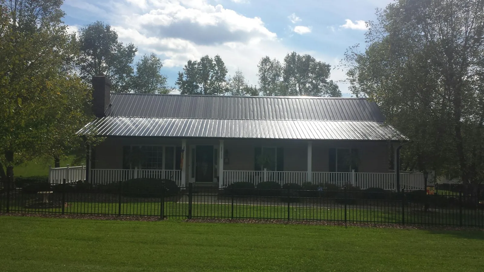 Gray metal roof on a brick ranch with a full width front porch — Gutter Guard Installation work by our crew in Tennessee Colony