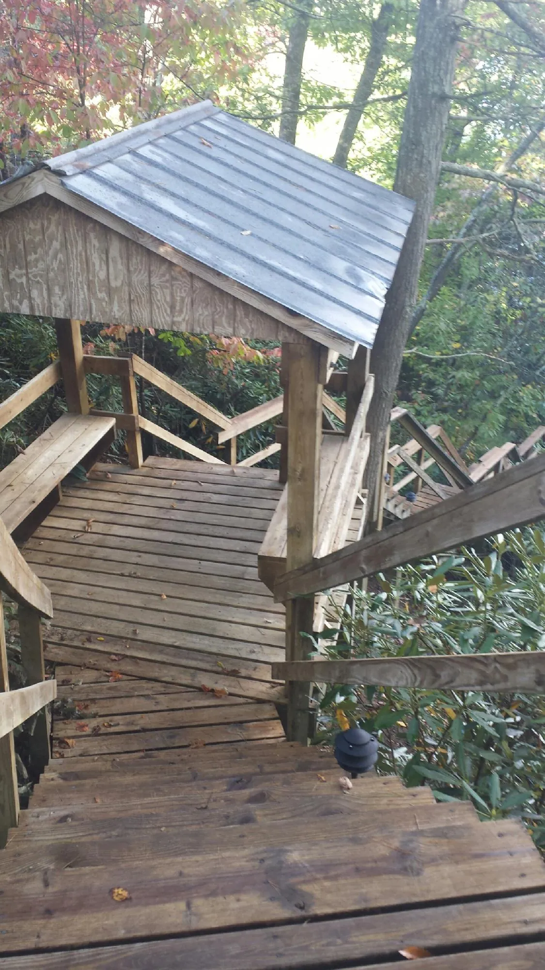 Metal roofed shelter over wooden steps on a wooded walkway — Skylight Repair & Installation work by our crew in Tennessee Colony