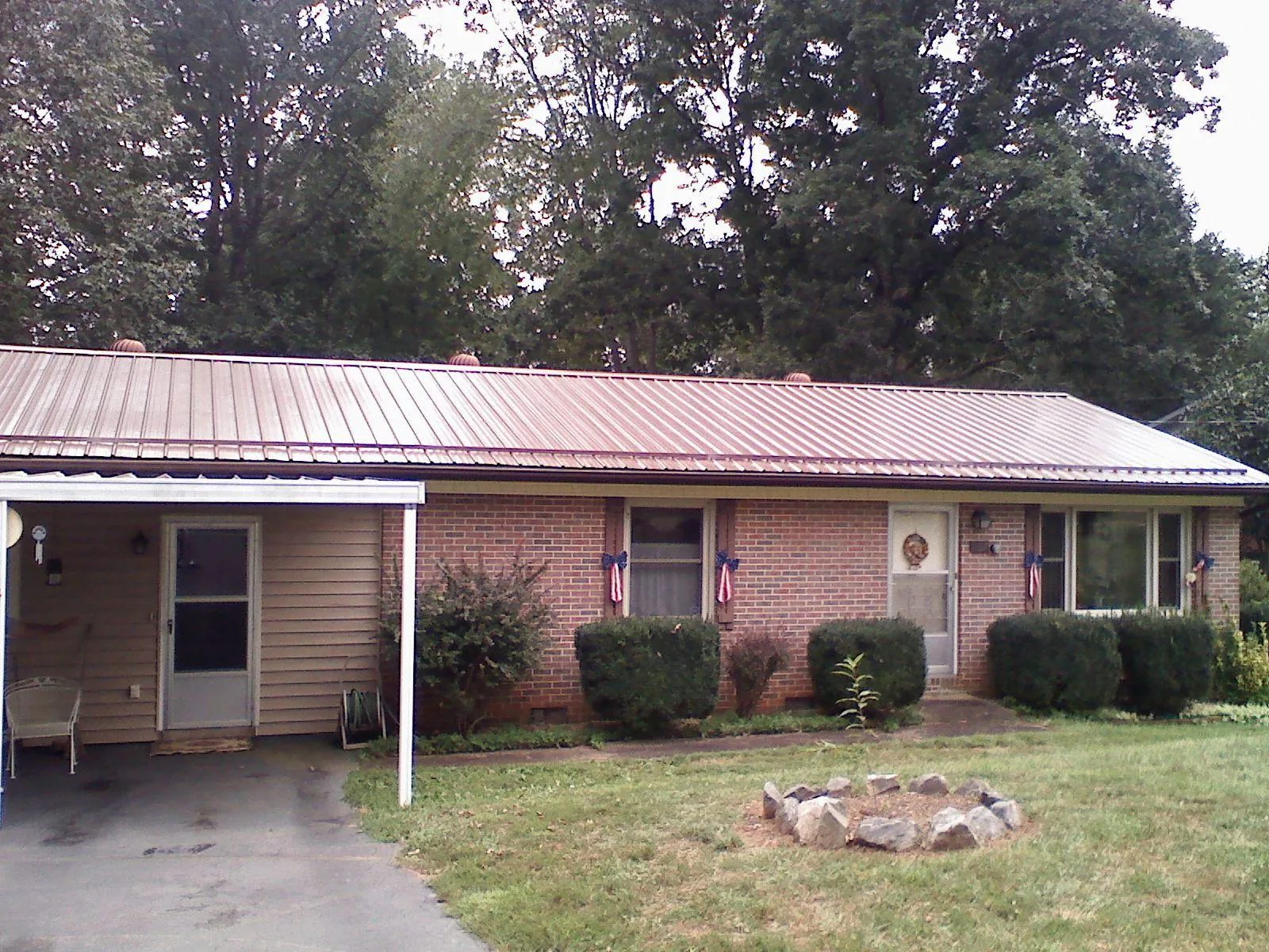 Bronze metal roof and carport on a brick ranch home — Roof Repair work by our crew in Tennessee Colony