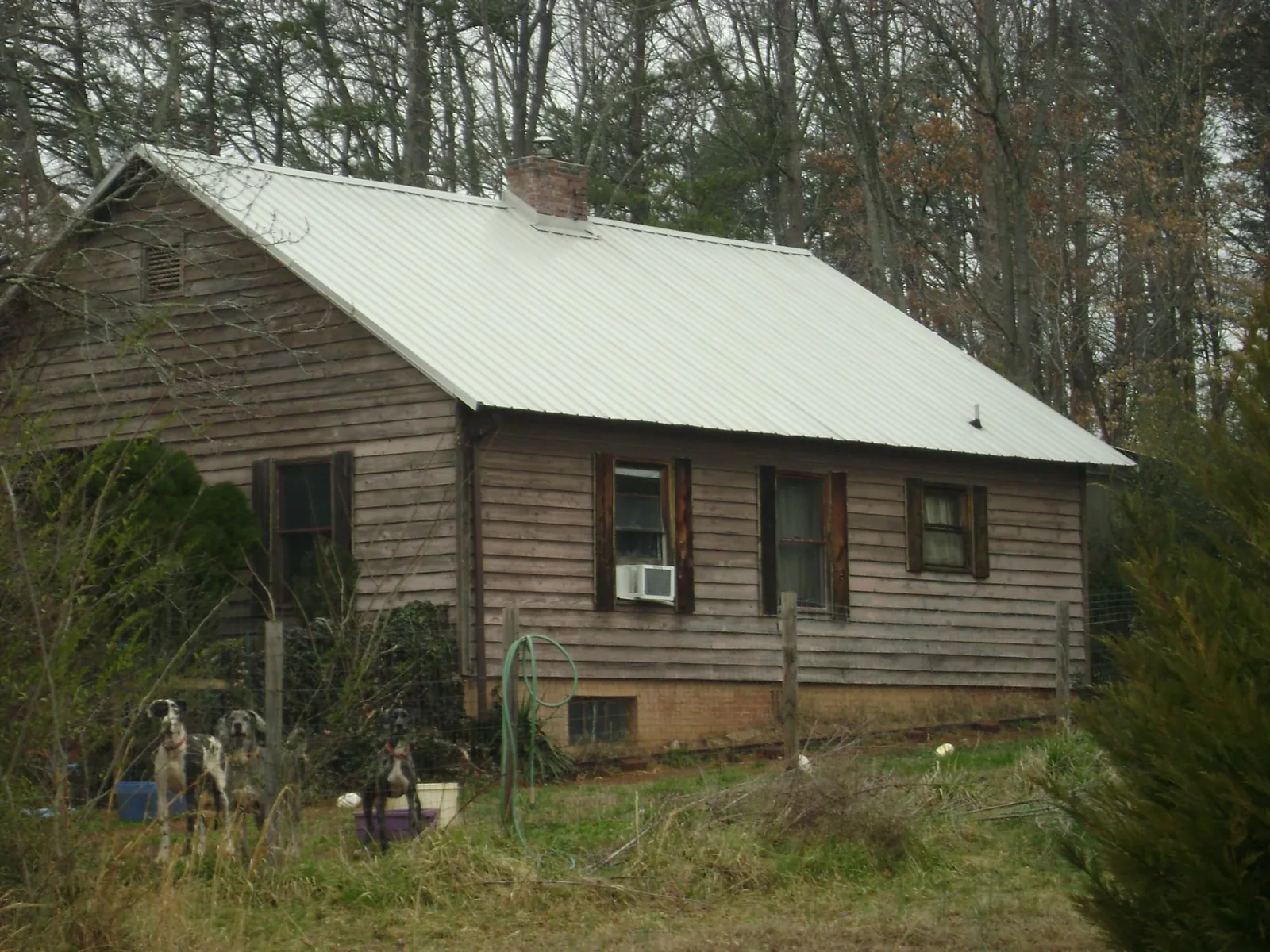 White metal roof on an old wood sided farmhouse, from a Asphalt Shingle Roof Repair job in Tennessee Colony