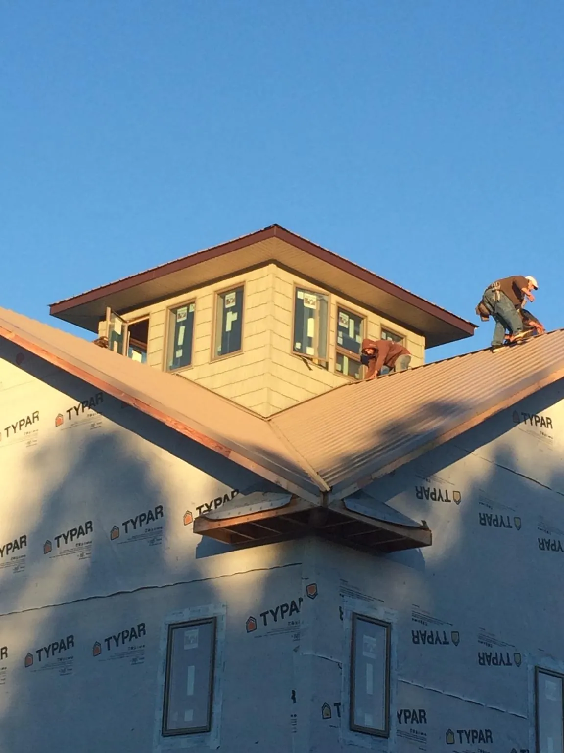 Roofers working around a rooftop cupola on a new metal roof at sunset — Roof Waterproofing in Tennessee Colony by Roofing Brothers